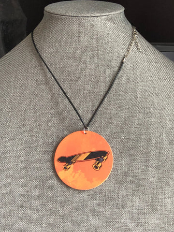 Collier breloque garçon rond bois modèle œil planche à roulette skate board fond orange Comme un ange